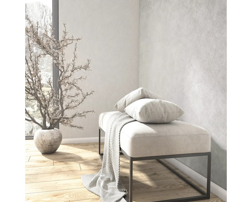 Helle, moderne Raumsituation mit gepolsterter Sitzbank auf Metallgestell, Kissen, Decke, Kunstpflanze im Topf und Holzboden.