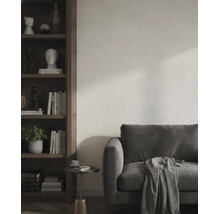 Modernes Wohnzimmer mit dunklem Sofa, gemusterter Decke und einem dunklen Holzregal vor einer hellen, strukturierten Wand.