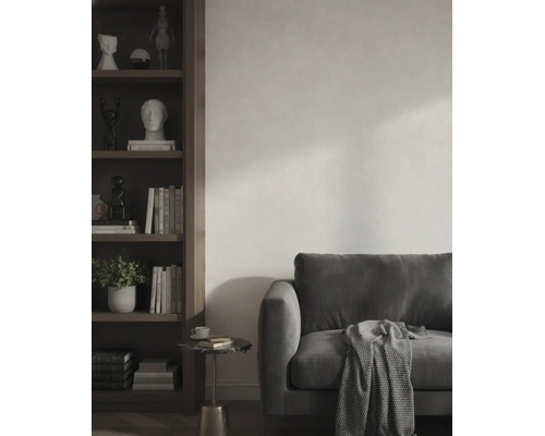 Modernes Wohnzimmer mit dunklem Sofa, gemusterter Decke und einem dunklen Holzregal vor einer hellen, strukturierten Wand.