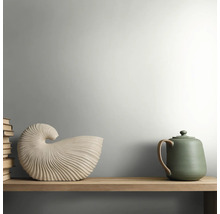 Holzregal mit einer muschelförmigen Keramikdekoration, einer grünen Teekanne und einem Stapel Bücher in einem hellen, minimalistischen Stil.