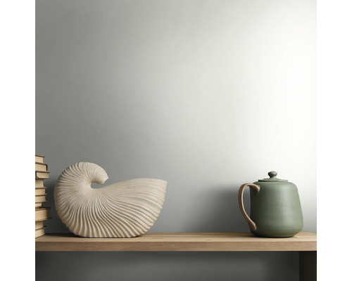 Holzregal mit einer muschelförmigen Keramikdekoration, einer grünen Teekanne und einem Stapel Bücher in einem hellen, minimalistischen Stil.
