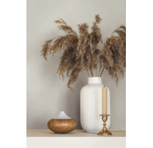 Geriffelte Vase mit getrocknetem Ziergras, ein Aroma-Diffuser aus Holz und ein Kerzenständer mit Kerze.