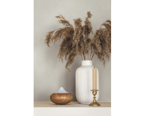 Geriffelte Vase mit getrocknetem Ziergras, ein Aroma-Diffuser aus Holz und ein Kerzenständer mit Kerze.