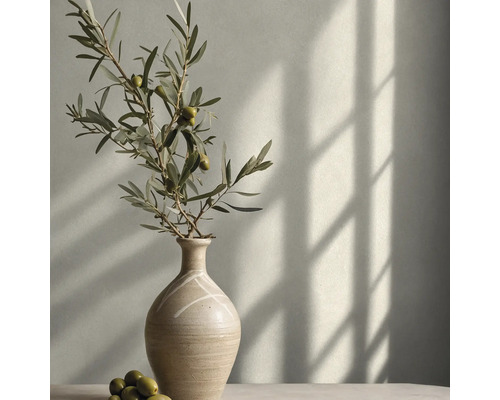 Minimalistische Keramikvase mit Olivenzweig und Oliven vor einer hellen Wand mit Fensterschatten.