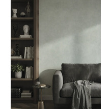 Wohnzimmer mit strukturierter Wand, Samtsofa und einem Holzregal mit dekorativen Objekten.