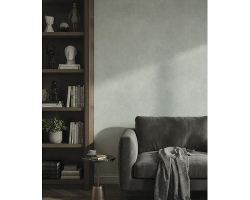 Wohnzimmer mit strukturierter Wand, Samtsofa und einem Holzregal mit dekorativen Objekten.