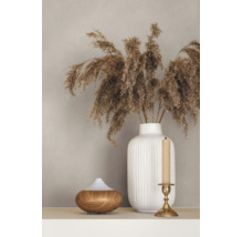 Weiße geriffelte Keramikvase mit getrocknetem Pampasgras, ein Aroma-Diffusor in Holzoptik und ein goldener Kerzenständer auf einer Ablage.