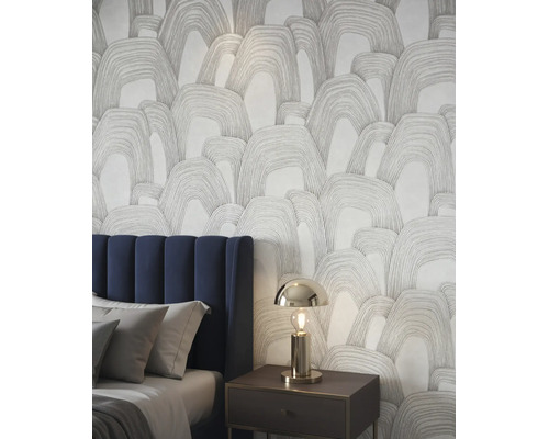 Vliestapete mit abstraktem Bogenmuster in einem modernen Schlafzimmer neben einem gepolsterten Bett mit blauem Kopfteil.