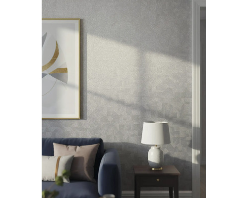 Modernes Wohnzimmer mit grauer Strukturtapete mit dezentem geometrischem Muster, blauem Sofa, Beistelltisch und Lampe.