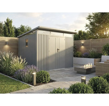 Modernes Metall-Gartenhaus mit Pultdach und Doppeltür in einer Gartenanlage mit Steinplatten-Terrasse, Feuerstelle und Zierpflanzen.