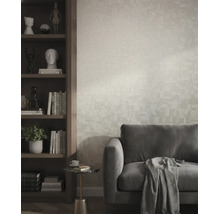 Strukturierte Vliestapete in einem modernen Wohnzimmer hinter einem grauen Sofa und neben einem dunklen Holzregal.