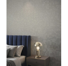 Schlafzimmer mit strukturierter Tapete, blauem Polsterkopfteil und moderner Tischleuchte aus Metall auf einem Nachttisch.
