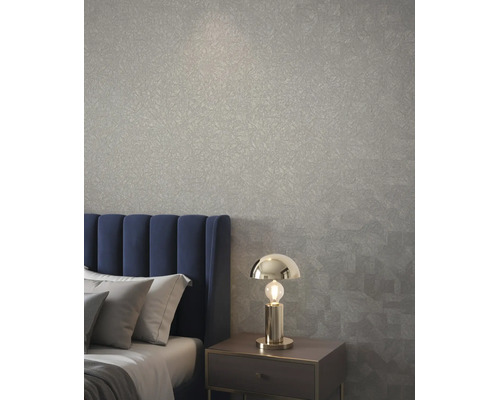 Schlafzimmer mit strukturierter Tapete, blauem Polsterkopfteil und moderner Tischleuchte aus Metall auf einem Nachttisch.