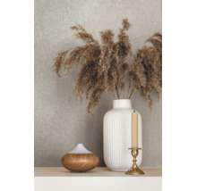 Strukturierte Tapete hinter einer Dekoration mit einer geriffelten Vase mit Trockengras, einem Diffuser in Holzoptik und einem Kerzenständer.