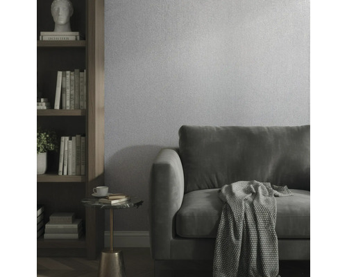 Modernes Wohnzimmer mit strukturierter Tapete, Samtsofa und Bücherregal aus Holz.