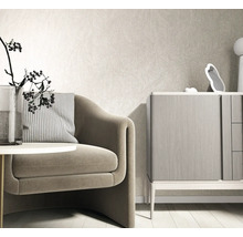 Modernes helles Wohnzimmer mit strukturierter Vliestapete an der Wand, einem Sessel mit gestreiftem Kissen und einer Kommode aus Holz.