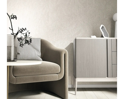 Modernes helles Wohnzimmer mit strukturierter Vliestapete an der Wand, einem Sessel mit gestreiftem Kissen und einer Kommode aus Holz.