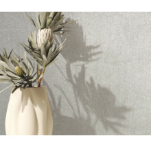 Strukturierte Tapete mit feinem Linienmuster an einer Wand neben einer Vase mit Blumen.