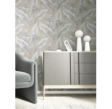 Vliestapete mit botanischem Blattmuster in einem modern eingerichteten Zimmer mit grauem Sideboard und Sessel.