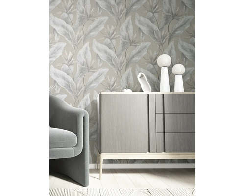 Vliestapete mit botanischem Blattmuster in einem modern eingerichteten Zimmer mit grauem Sideboard und Sessel.