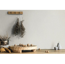 Hell strukturierte Wand mit rustikaler Dekoration, Holzbrett, Walnüssen, getrockneten Kräutern und Steinfrüchten auf einem Holztisch.