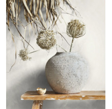 Runde Keramikvase mit strukturierter Oberfläche und Trockenblumen auf einer Holzbank.