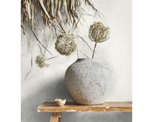 Runde Keramikvase mit strukturierter Oberfläche und Trockenblumen auf einer Holzbank.