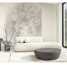 Helles, modernes Wohnzimmer mit großflächiger Fototapete mit abstraktem Blumenmotiv, weißem geschwungenem Sofa und dunklen runden Tischen.