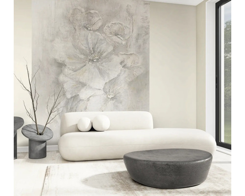 Helles, modernes Wohnzimmer mit großflächiger Fototapete mit abstraktem Blumenmotiv, weißem geschwungenem Sofa und dunklen runden Tischen.
