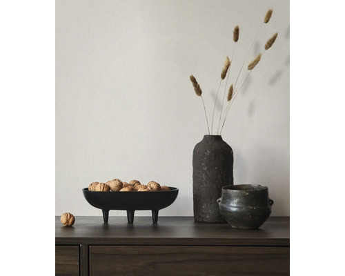 Sideboard aus dunklem Holz mit einer dekorativen schwarzen Schale auf drei Beinen gefüllt mit Walnüssen, einer Vase mit Trockengras und einem Topf.