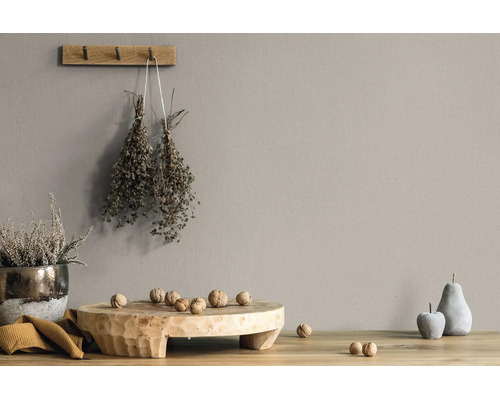 Wandfarbe in Taupe in einem rustikalen Wohnambiente mit Holzbrett, Walnüssen und getrockneten Kräutern.