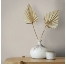 Minimalistische Dekoration mit gesprenkelter Keramikvase, zwei getrockneten Palmwedeln und kleinem Keramikgefäß auf einer Holzoberfläche.