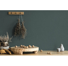 Dunkelgrün gestrichene Wand mit rustikaler Dekoration aus Holz, getrockneten Kräutern und Walnüssen auf einem Holztisch.