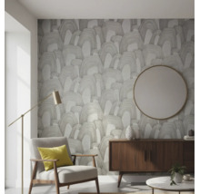 Vliestapete mit abstraktem Bogenmuster in einem modernen Wohnzimmer mit Polstersessel, Sideboard und rundem Wandspiegel.