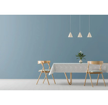 Modern eingerichtetes Esszimmer mit blau gestrichener Wand, Holztisch mit Tischdecke, zwei Stühlen und drei konischen Hängeleuchten.