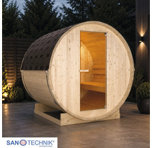 Sanotechnik Fasssauna aus Holz auf einer Terrasse bei Dämmerung mit Glastür, Innenbeleuchtung und Dachschindeln. Sanotechnik Logo.