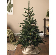 Dekorierter Christbaum in einem Wohnzimmer mit grünen matten und glänzenden Weihnachtskugeln sowie einer Baumdecke aus Stoff.