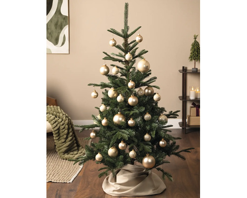 Christbaum dekoriert mit verschieden großen, glänzenden Kugeln in einem hellen Wohnraum mit Holzfußboden.