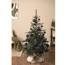 Kleiner grüner Weihnachtsbaum mit dunkelvioletten Christbaumkugeln in einem hellen Wohnzimmer mit gemütlicher Atmosphäre.