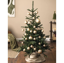 Christbaum dekoriert mit verschieden großen, glänzenden Kugeln in einem hellen Wohnraum mit Holzfußboden.