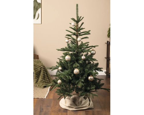 Weihnachtsbaum mit champagnerfarbenen Kugeln und Schneeflockenmuster in einem Wohnzimmer auf Holzboden.