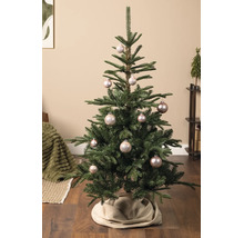 Dekorierter Weihnachtsbaum mit glänzenden Christbaumkugeln und einer Baumdecke in einem hellen, gemütlichen Wohnzimmer.