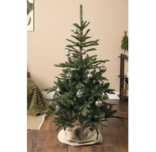 Künstlicher Weihnachtsbaum mit silbernen Kugeln mit Schneeflockenmuster auf Holzboden in einem organisierten Wohnbereich.