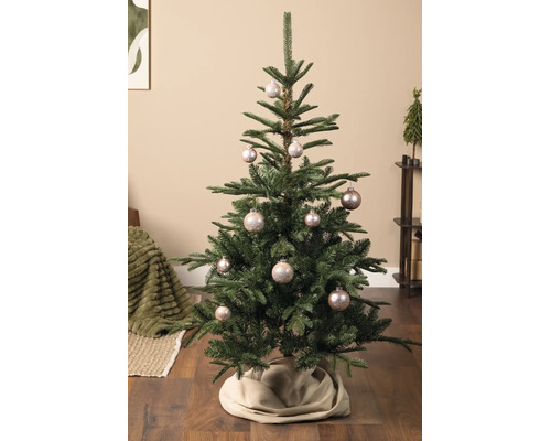 Dekorierter Weihnachtsbaum mit glänzenden Christbaumkugeln und einer Baumdecke in einem hellen, gemütlichen Wohnzimmer.