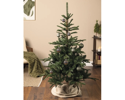 Künstlicher Christbaum mit gemusterten Kugeln in einem gemütlich eingerichteten Wohnzimmer mit Holzboden und Weihnachtsdekoration.