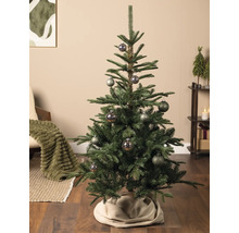 Künstlicher Christbaum mit gemusterten Kugeln in einem gemütlich eingerichteten Wohnzimmer mit Holzboden und Weihnachtsdekoration.