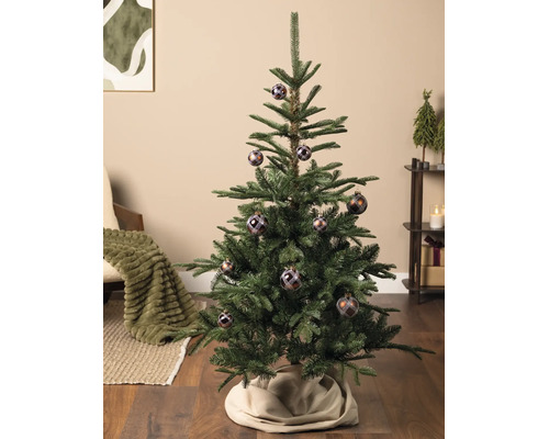 Ein künstlicher Weihnachtsbaum geschmückt mit karierten Kugeln in einem hellen, aufgeräumten Wohnzimmer.