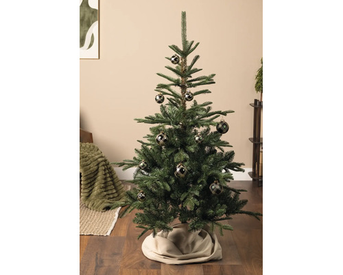 Geschmückter künstlicher Weihnachtsbaum mit dunklen Christbaumkugeln mit Karomuster in einem Wohnraum mit Holzboden.