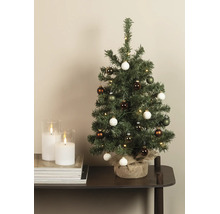 Kleiner künstlicher Weihnachtsbaum mit LED-Beleuchtung und Kugeln, Standfuß mit Jute umwickelt, auf einem Tisch neben Kerzen.