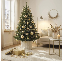 Geschmückter Weihnachtsbaum mit Sternen und Kugeln in einem hellen, organisierten Wohnzimmer. Der Baum steht in einer Strickhülle neben einem Sofa.